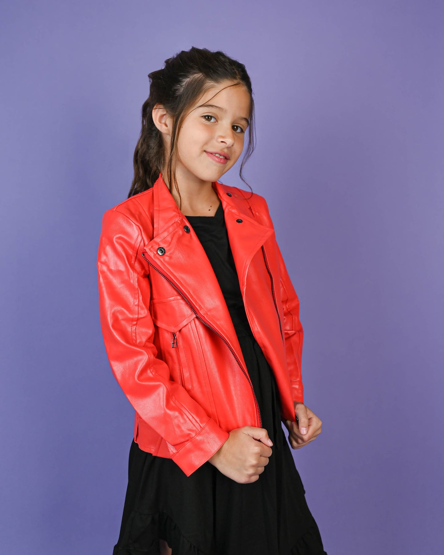 Confident young girl wearing a striking red leather jacket, paired perfectly with a black dress, radiating bold and stylish energy.