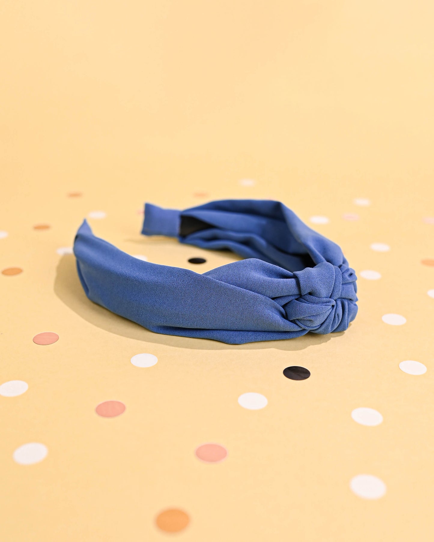 Blue top knot headband at an angle, with polka dots in the backdrop.