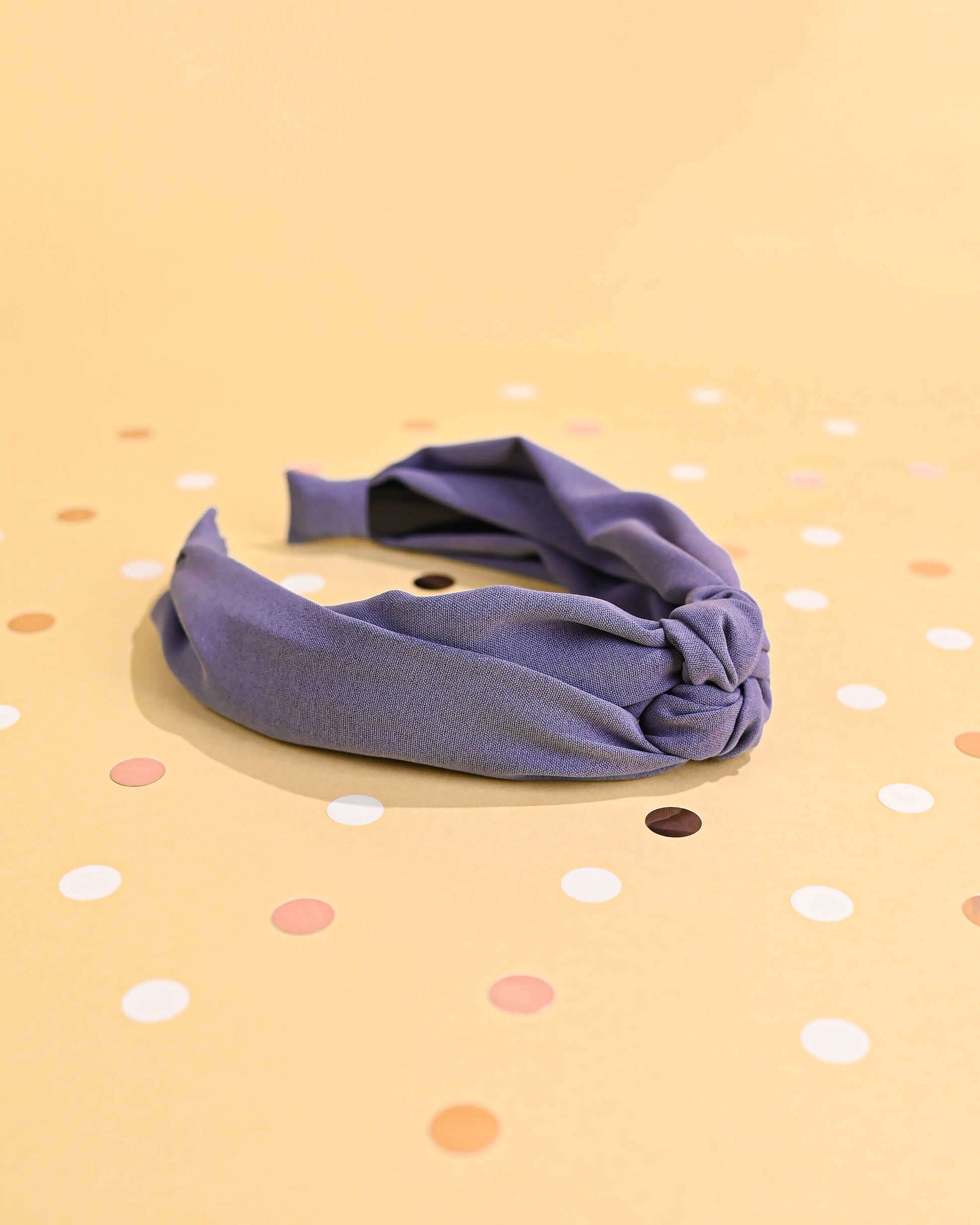 Purple top knot headband at an angle, with polka dots in the backdrop.