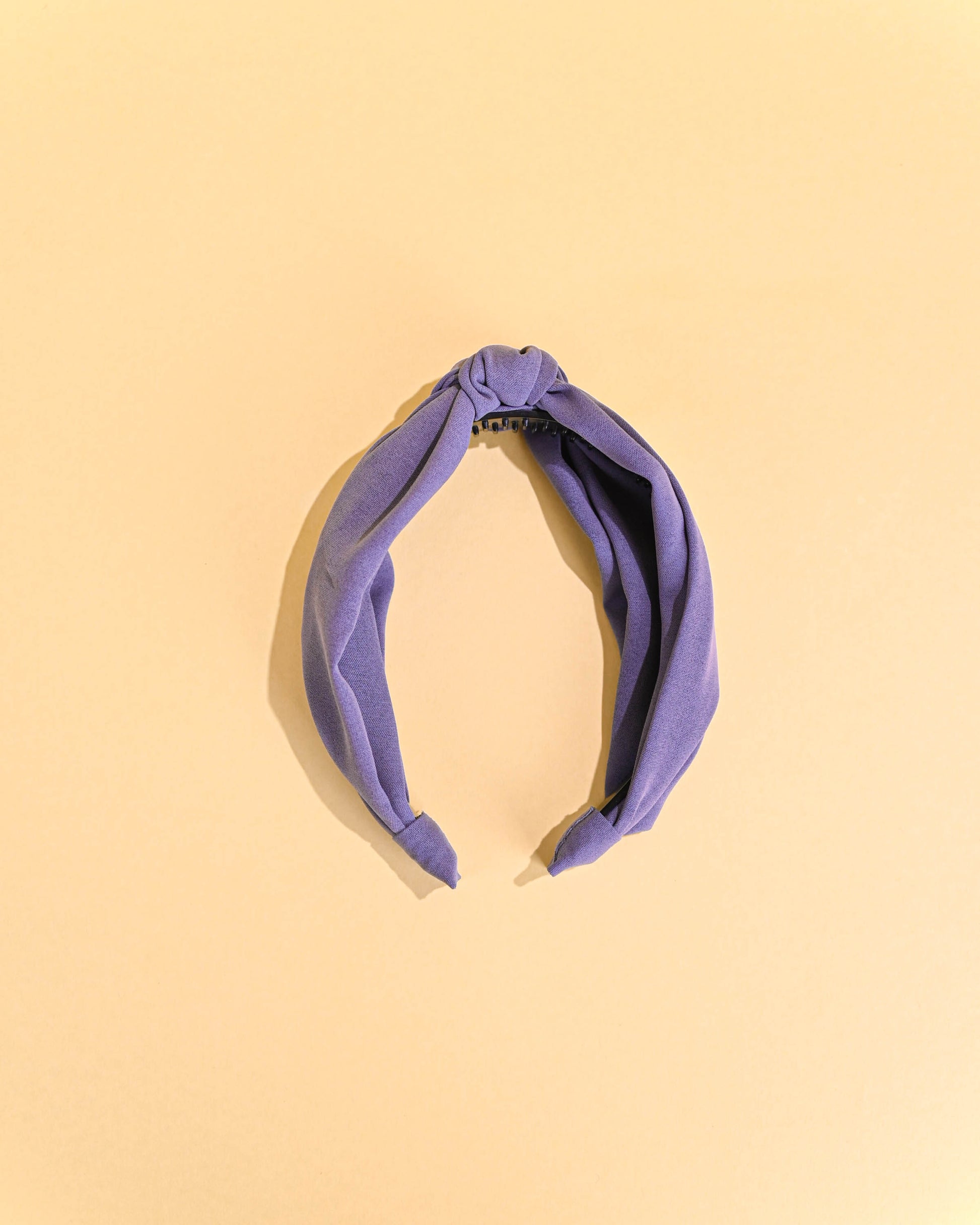 Purple top knot headband on a yellow background.