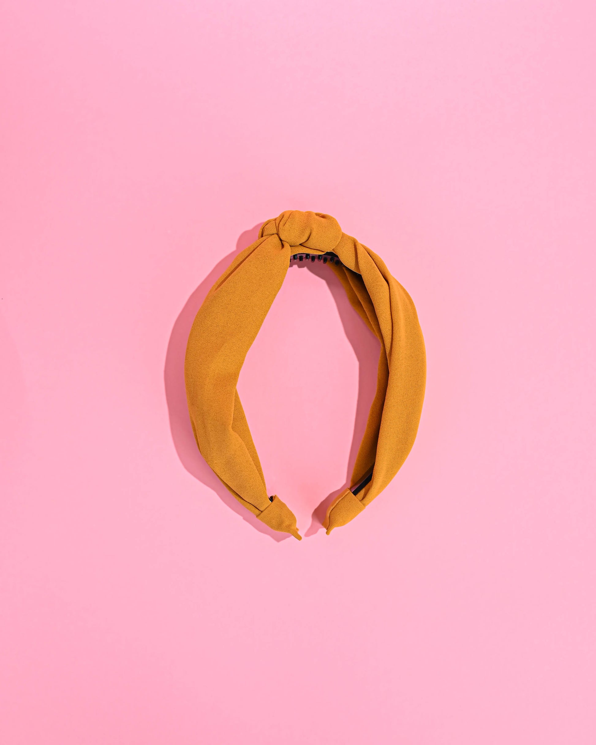 Yellow top knot headband on a yellow background.