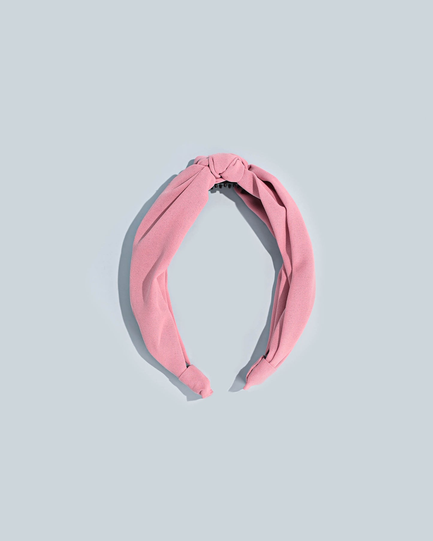 Pink top knot headband presented on a light blue background.