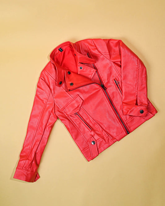 Bright red leather jacket lying flat on a warm yellow background, highlighting its vibrant color and trendy design.