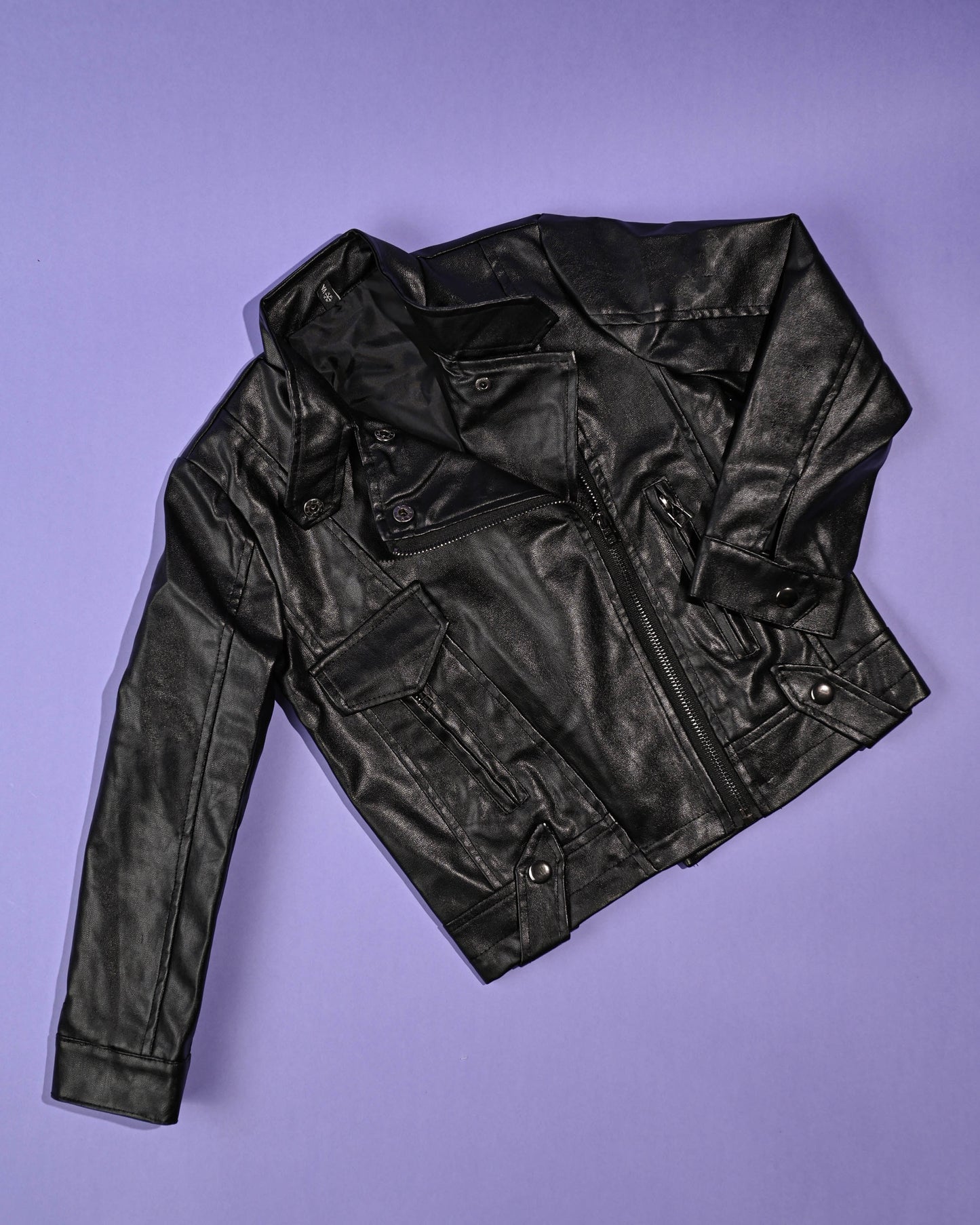 Classic black leather jacket against a purple background, exuding an edgy yet kid-friendly fashion vibe.