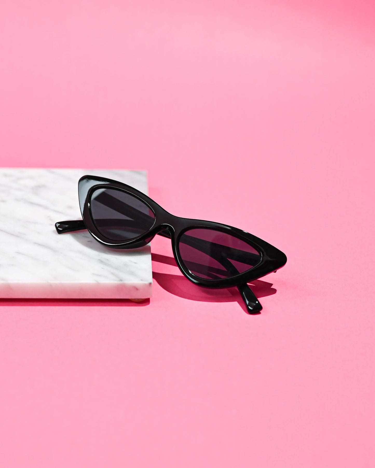 Elegant black cat-eye sunglasses on a pink background, embodying a sleek and retro vibe perfect for any fashion-forward ensemble.