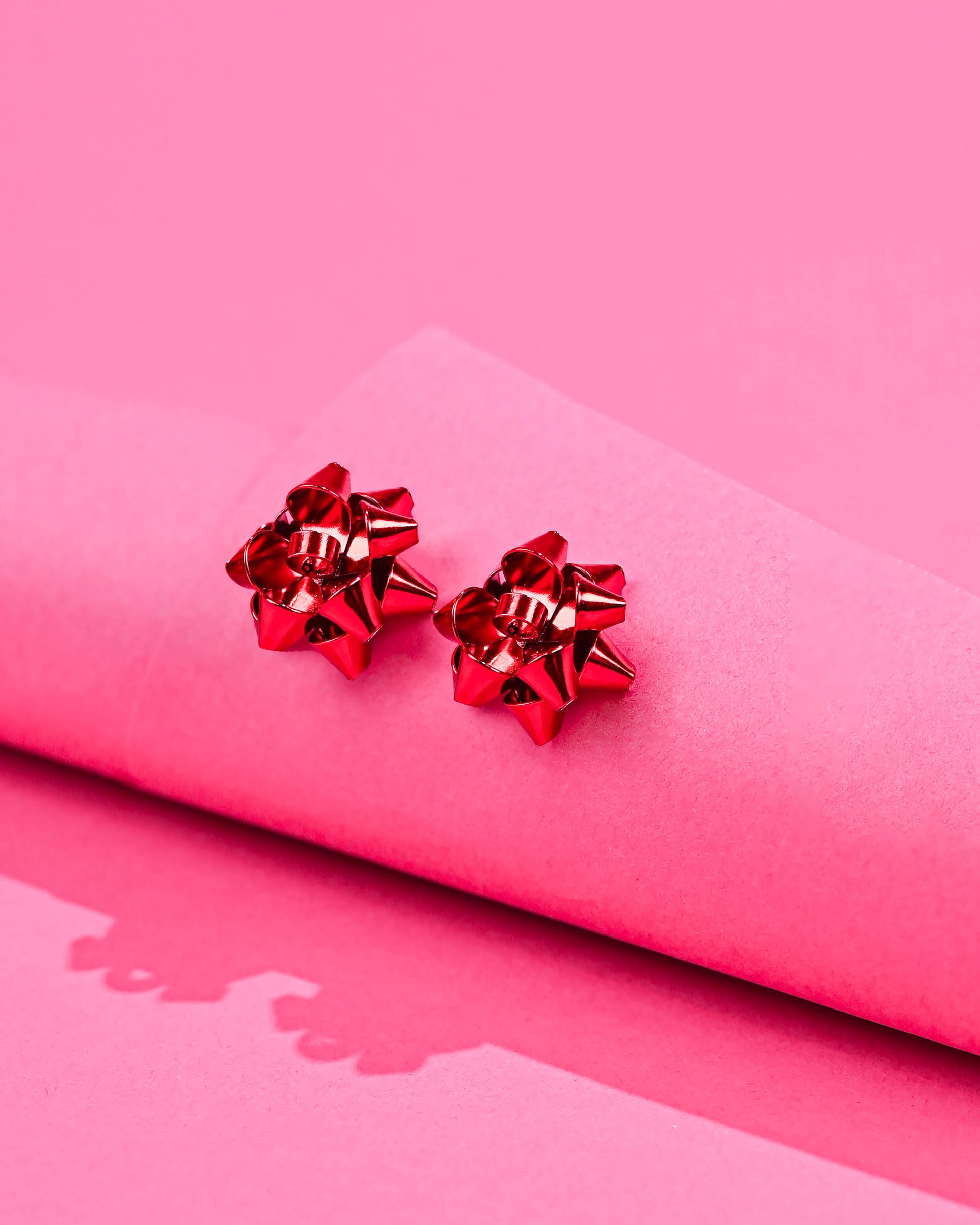 Charming red Bow Earrings on a pink background, perfect for adding a pop of color to any outfit