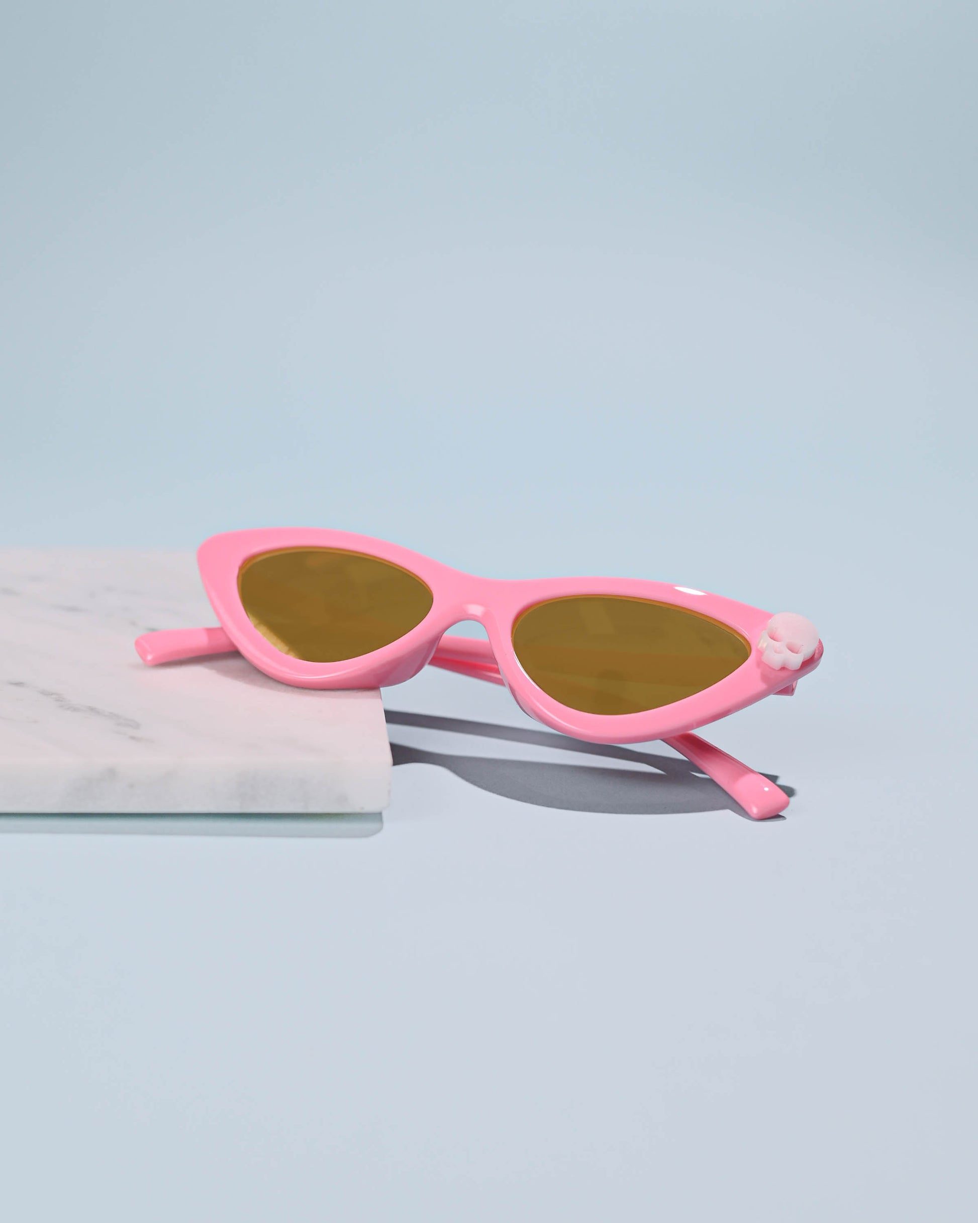 Pink Skull Cat Eye Sunglasses with a vintage flair, displayed on a marble slab for a stylish presentation.